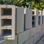 Konstrukcja muru ogrodzeniowego z klinkierowymi słupkami i betonowym fundamentem – stalowe przęsła jako wykończenie