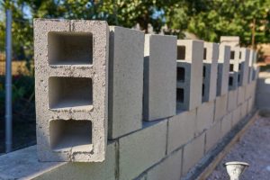 Konstrukcja muru ogrodzeniowego z klinkierowymi słupkami i betonowym fundamentem – stalowe przęsła jako wykończenie